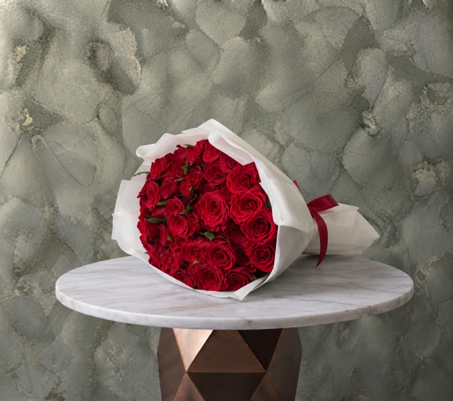 Red roses amman featuring a lush bouquet of premium red roses in white wrapping paper with a red ribbon.جوري الاحمر