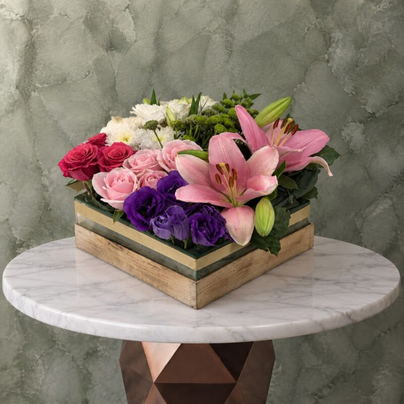 Luxurious flowers in a glass box with wooden base featuring pink lilies and purple flowers in Amman-زهور فاخرة في بوكس زجاجي محاط بإطار خشبي أنيق يتضمن ليليوم وردي وزهور بنفسجية في عمان.