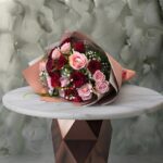 Red and pink roses amman bouquet featuring striking red and soft pink roses with baby's breath in elegant wrapping.