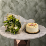 Carrot cake with white flower amman beautifully decorated with cream alongside an elegant wrapped floral bouquet.كيكة الجزر مع بوكية زهور بيضاء في عمان