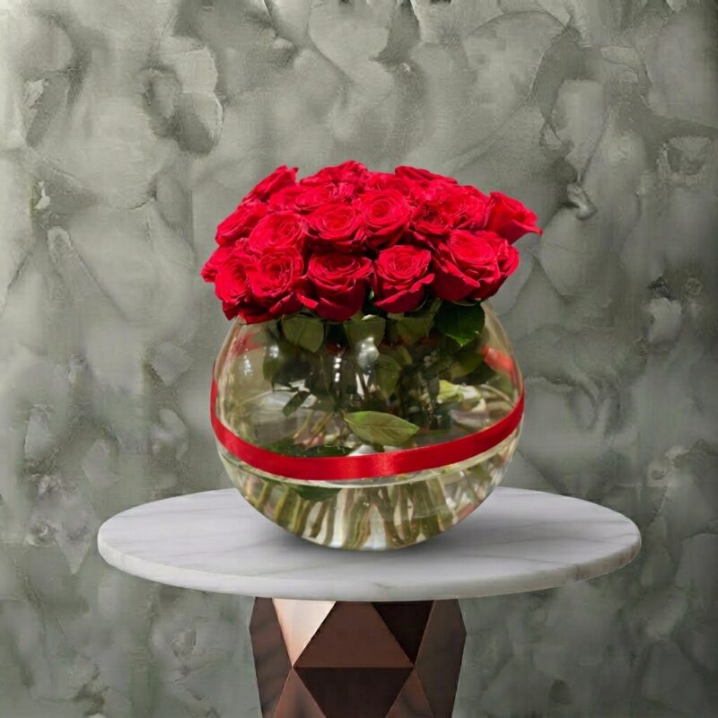 Elegant red love vase with 30 red roses in a spherical glass bowl with a red ribbon in Amman. مزهرية حب الحمراء زجاجية كروية تحتوي على 30 وردة جورية حمراء فاخرة وشريط أحمر في عمان.