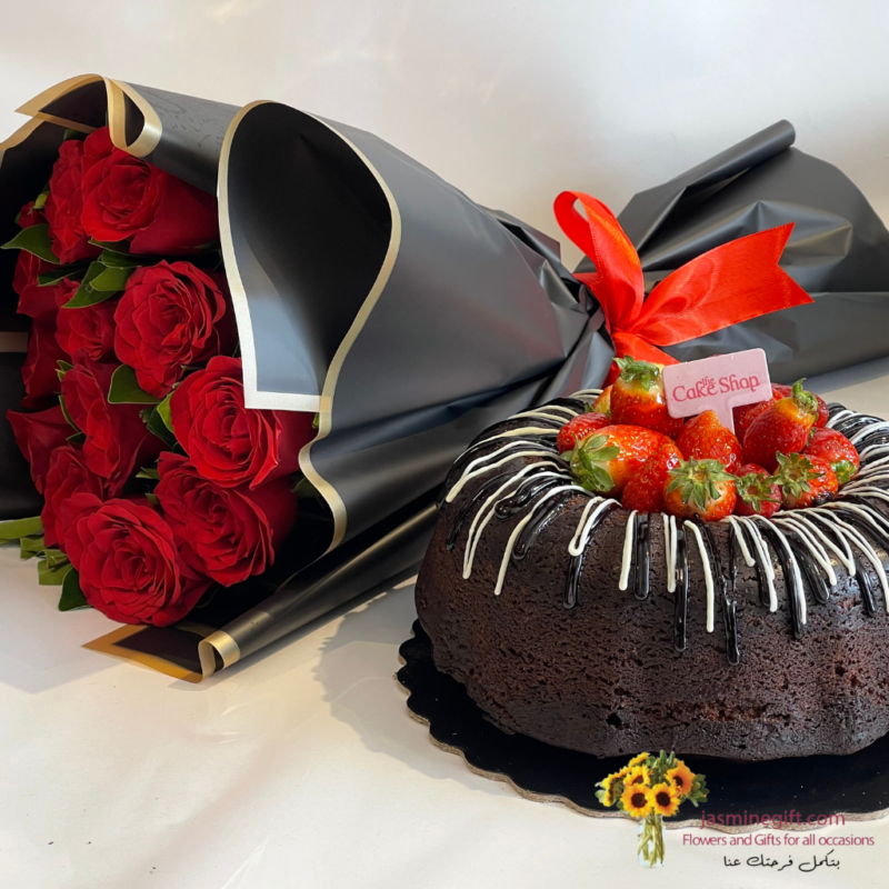 Red roses with chocolate cake topped with fresh strawberries and black luxury wrapping paper.