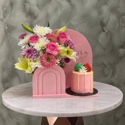 هدية مولود جديد بنت مع زهور وكيكة ريد فيلفيت وردية بقطع ماكارون وردية مصغرة في عمان.A new baby girl gift set with flowers and a red velvet pink cake with mini pink macarons in Amman