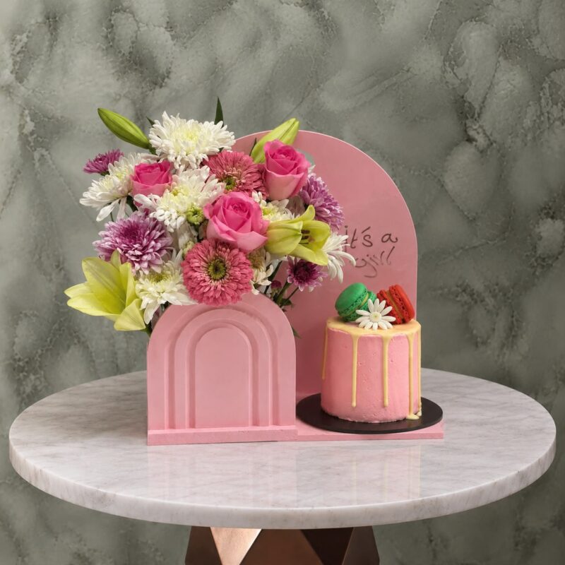 هدية مولود جديد بنت مع زهور وكيكة ريد فيلفيت وردية بقطع ماكارون وردية مصغرة في عمان.A new baby girl gift set with flowers and a red velvet pink cake with mini pink macarons in Amman