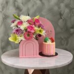 هدية مولود جديد بنت مع زهور وكيكة ريد فيلفيت وردية بقطع ماكارون وردية مصغرة في عمان.A new baby girl gift set with flowers and a red velvet pink cake with mini pink macarons in Amman
