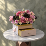 Magic of details amman featuring pink floral arrangement with pinecones and a chocolate drawer box.