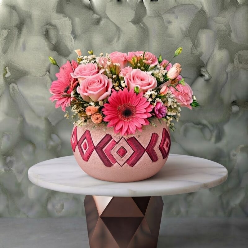 Handmade pink and floral jar amman featuring light pink roses, vibrant pink gerberas, and baby's breath in a patterned ceramic pot.