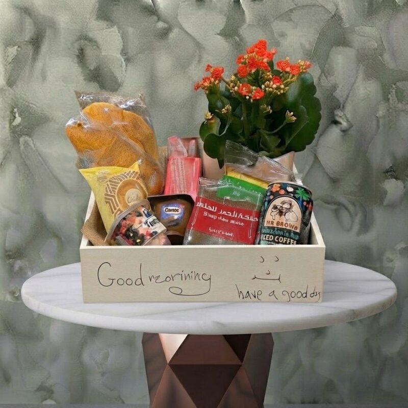 Morning bliss hamper amman featuring a charming mini plant, croissants, juices, cakes, and coffee in a wooden box. بوكس صباح السعادة