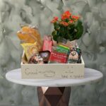 Morning bliss hamper amman featuring a charming mini plant, croissants, juices, cakes, and coffee in a wooden box. بوكس صباح السعادة