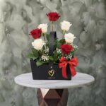 Just love amman arrangement featuring a stunning mix of red and white roses, baby's breath, and greenery in a black handle box with a red bow.
