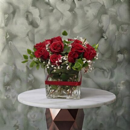 Classic red amman arrangement featuring fresh red roses, white baby's breath, and greenery in a square glass vase tied with a red ribbon.كلاسيك ريد