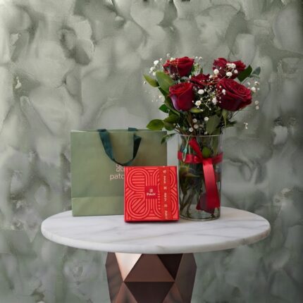Love pulse amman gift set featuring a cylindrical glass vase with red roses, baby's breath, a Patchi chocolate box, and a branded bag.