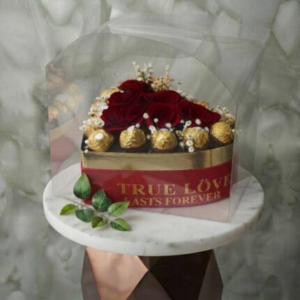 True love heart amman arrangement featuring red roses and golden-wrapped chocolates in a heart-shaped gift box with clear cover. قلب الحب الحقيقي