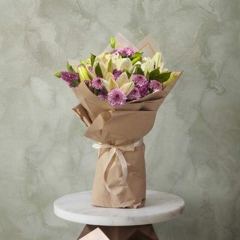 White lilies bouquet amman with purple chrysanthemums wrapped in brown kraft paper on a marble table.ليليوم أبيض و كريز نهدي زهري