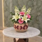 دفء الأم يضم زهور الليليوم البيضاء والجربيرا الوردية في وعاء بـ عمان-Mother's Warmth featuring white lilies and pink gerberas in a bowl in Amman