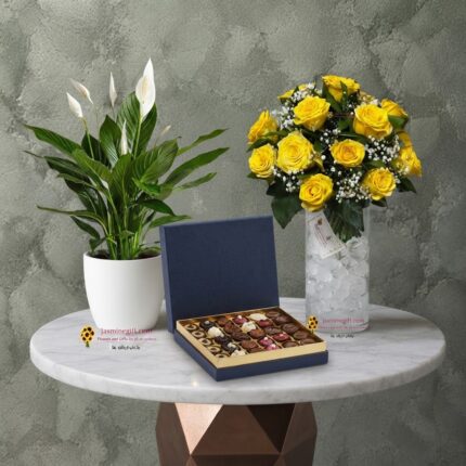 Fathers day gift amman featuring a yellow rose vase, a peace lily plant, and a luxury chocolate box on a marble table.