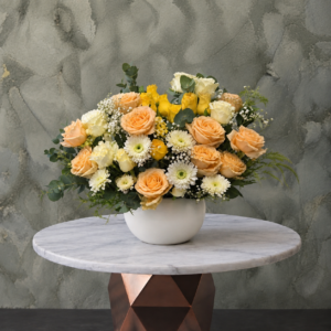 Golden rose arrangement amman featuring yellow and cream roses with white gerberas in a white ceramic vase.تنسيق الجوري الأصفر