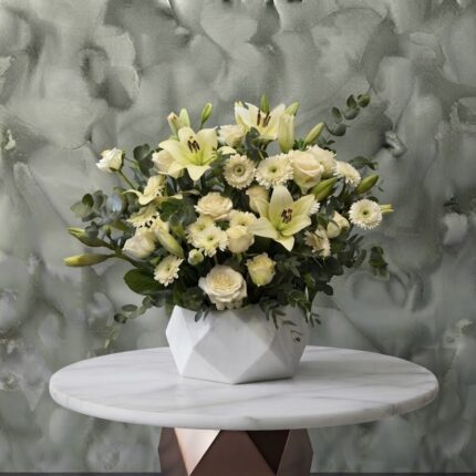 Pristine white blossoms amman featuring white lilies, roses, and gerberas in a geometنقاء الزهور البيضاءric ceramic vase.