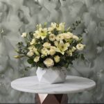Pristine white blossoms amman featuring white lilies, roses, and gerberas in a geometنقاء الزهور البيضاءric ceramic vase.